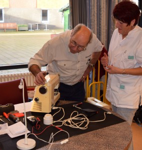 Een medewerkster van de Marente-huizen buigt zich met vrijwillig reparateur Cees Juffermans over een stilgevallen naaimachine