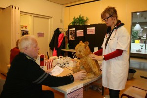 Heer A. de Vink houdt de oude teddybeer vast terwijl ‘poppendokter’ Heleen de Visser de oren er weer aannaait, tijdens het Repair Café van zaterdag 25 januari in de Gevers-Deutz Terweeschool. Foto PR 